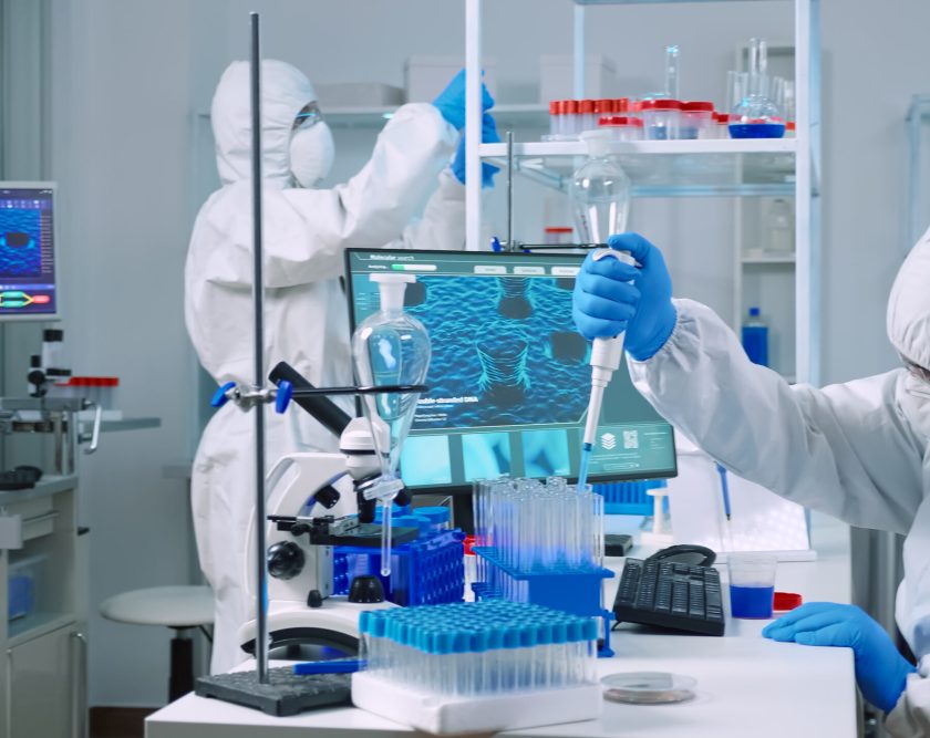 Scientist wearing coverall in equipped medical laboratory examining drug discovery with micropipette. Biochemists analysing virus evolution using high tech researching vaccine against covid19
